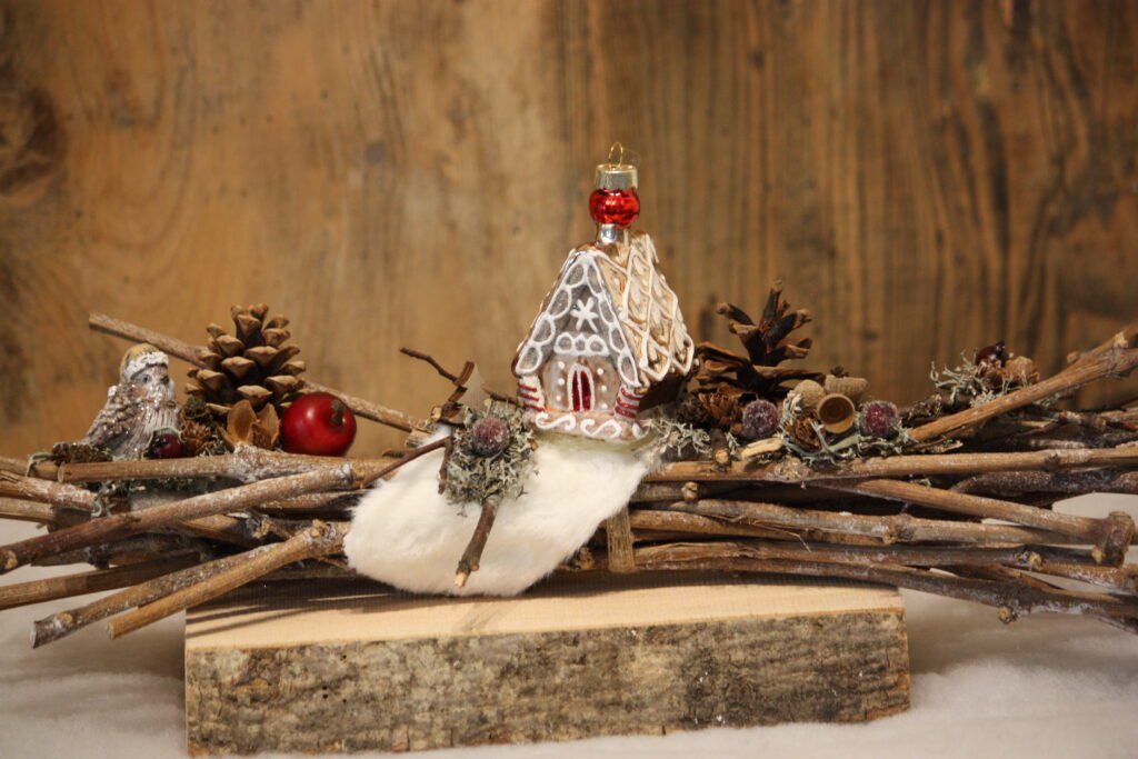 Arrangement de Noël -La petite maison pain d’épice au milieu des pommes de pin